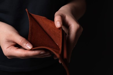 Photo of Woman with empty wallet on dark background, closeup