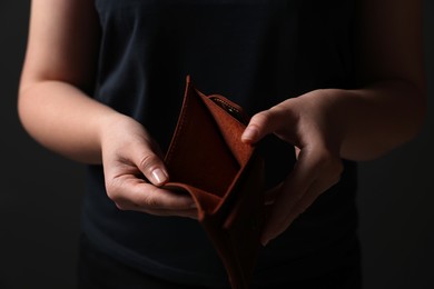 Photo of Woman with empty wallet on dark background, closeup