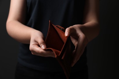 Photo of Woman with empty wallet on dark background, closeup