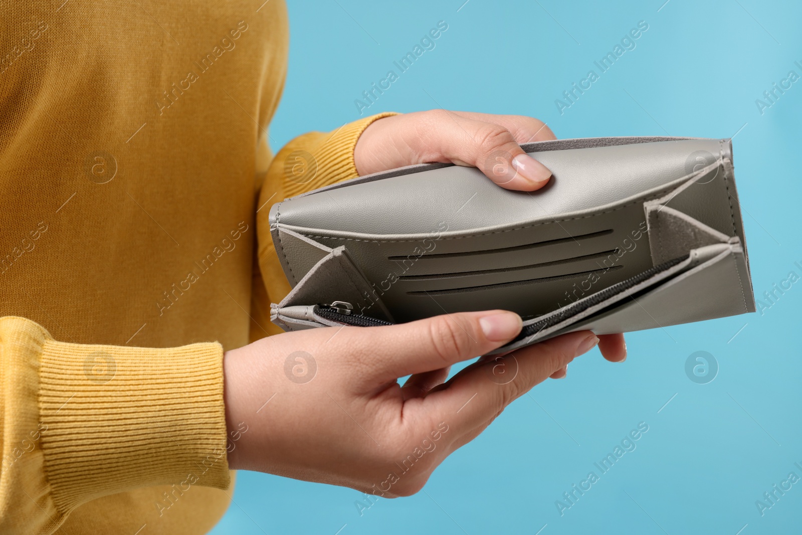 Photo of Woman with empty wallet on light blue background, closeup