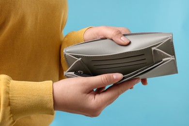 Photo of Woman with empty wallet on light blue background, closeup