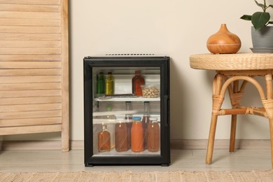 Photo of Mini refrigerator with drinks and snacks indoors