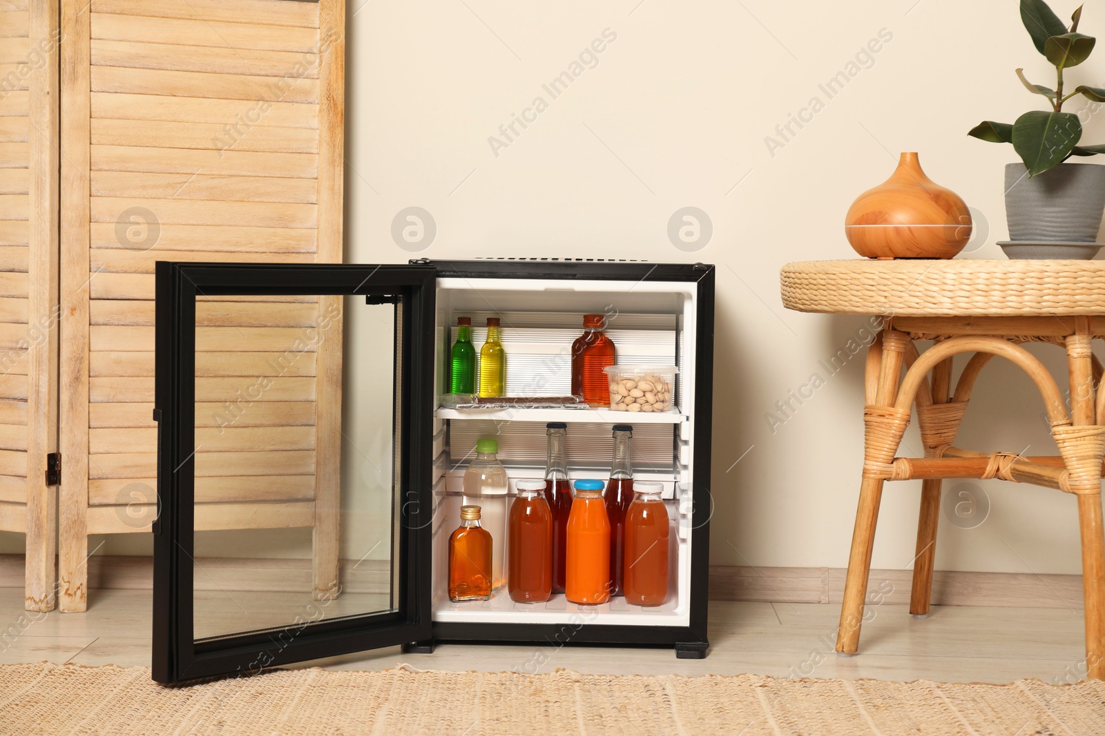 Photo of Mini refrigerator with drinks and snacks indoors