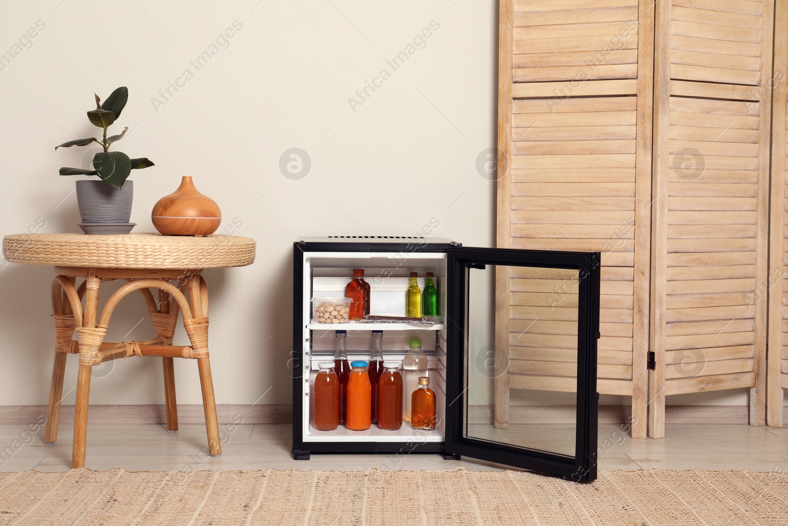 Photo of Mini refrigerator with drinks and snacks indoors