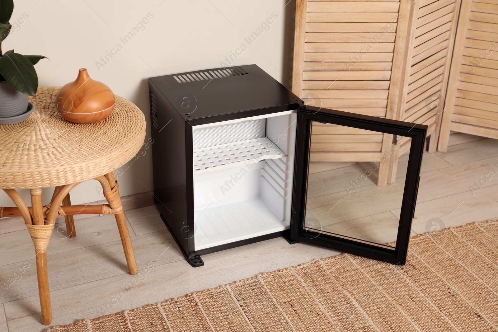 Photo of Empty modern mini refrigerator near beige wall indoors