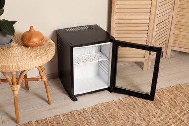 Photo of Empty modern mini refrigerator near beige wall indoors