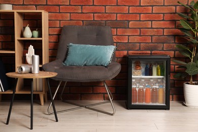 Photo of Mini refrigerator with drinks and snacks indoors