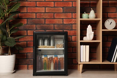 Photo of Mini refrigerator with drinks and snacks indoors