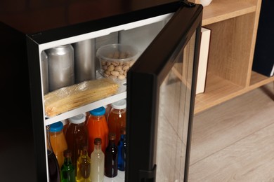 Mini refrigerator with drinks and snacks indoors, closeup