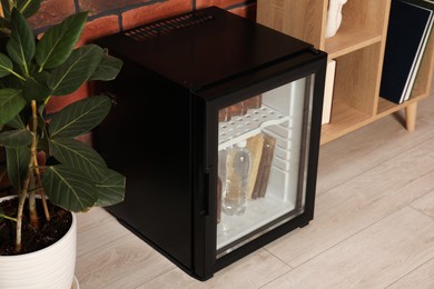 Photo of Mini refrigerator with drinks and snacks indoors