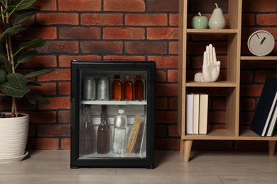 Photo of Mini refrigerator with drinks and snacks indoors