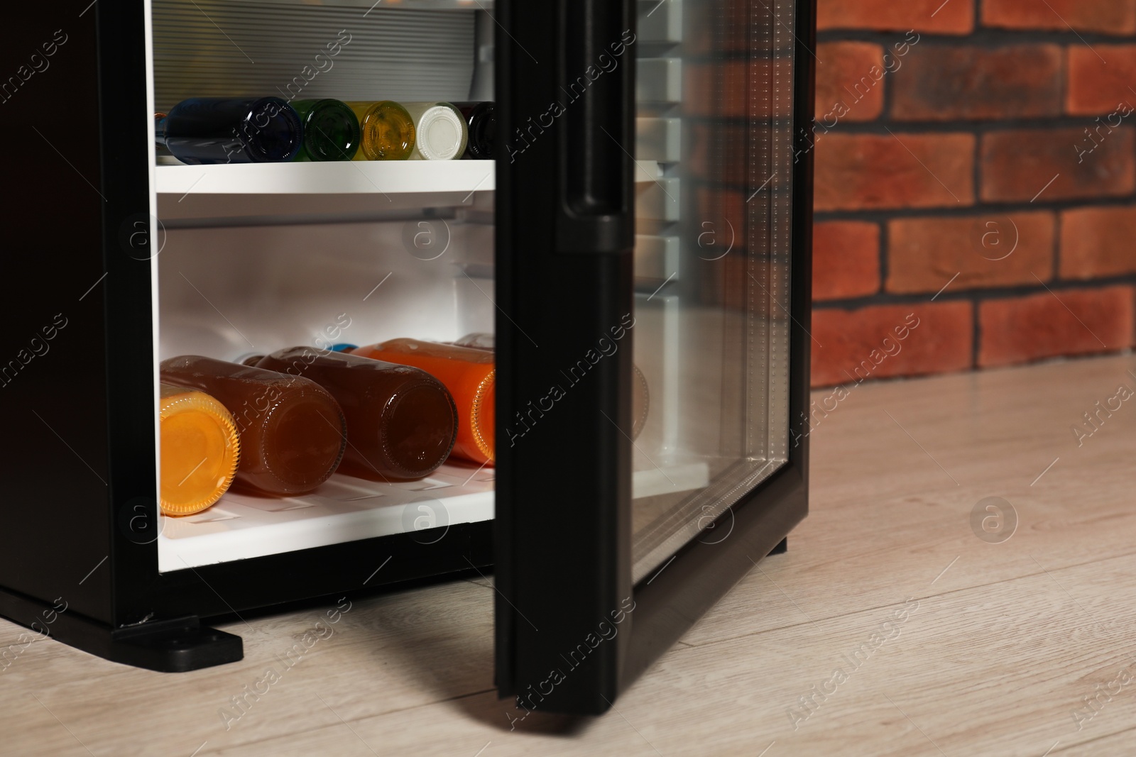 Photo of Mini refrigerator with drinks near brick wall, closeup