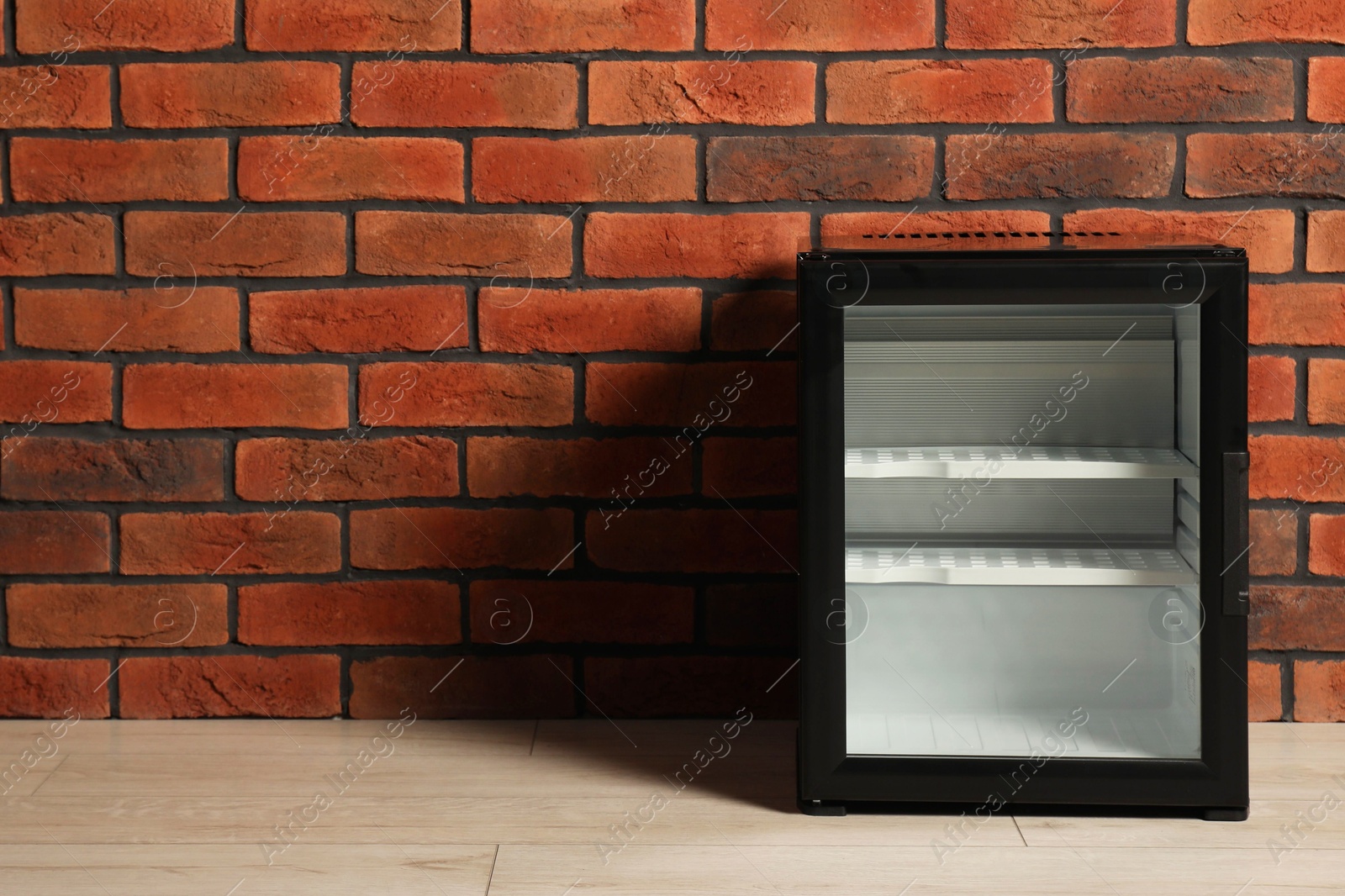 Photo of Empty mini refrigerator near brick wall. Space for text