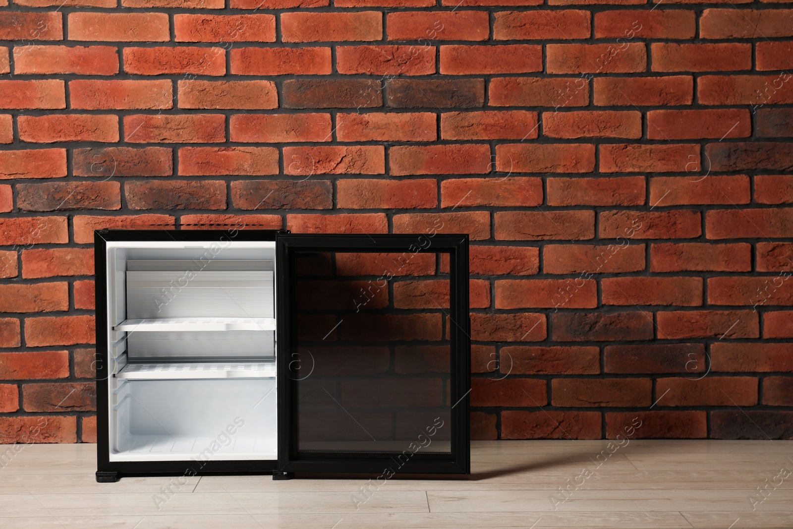 Photo of Empty mini refrigerator near brick wall. Space for text