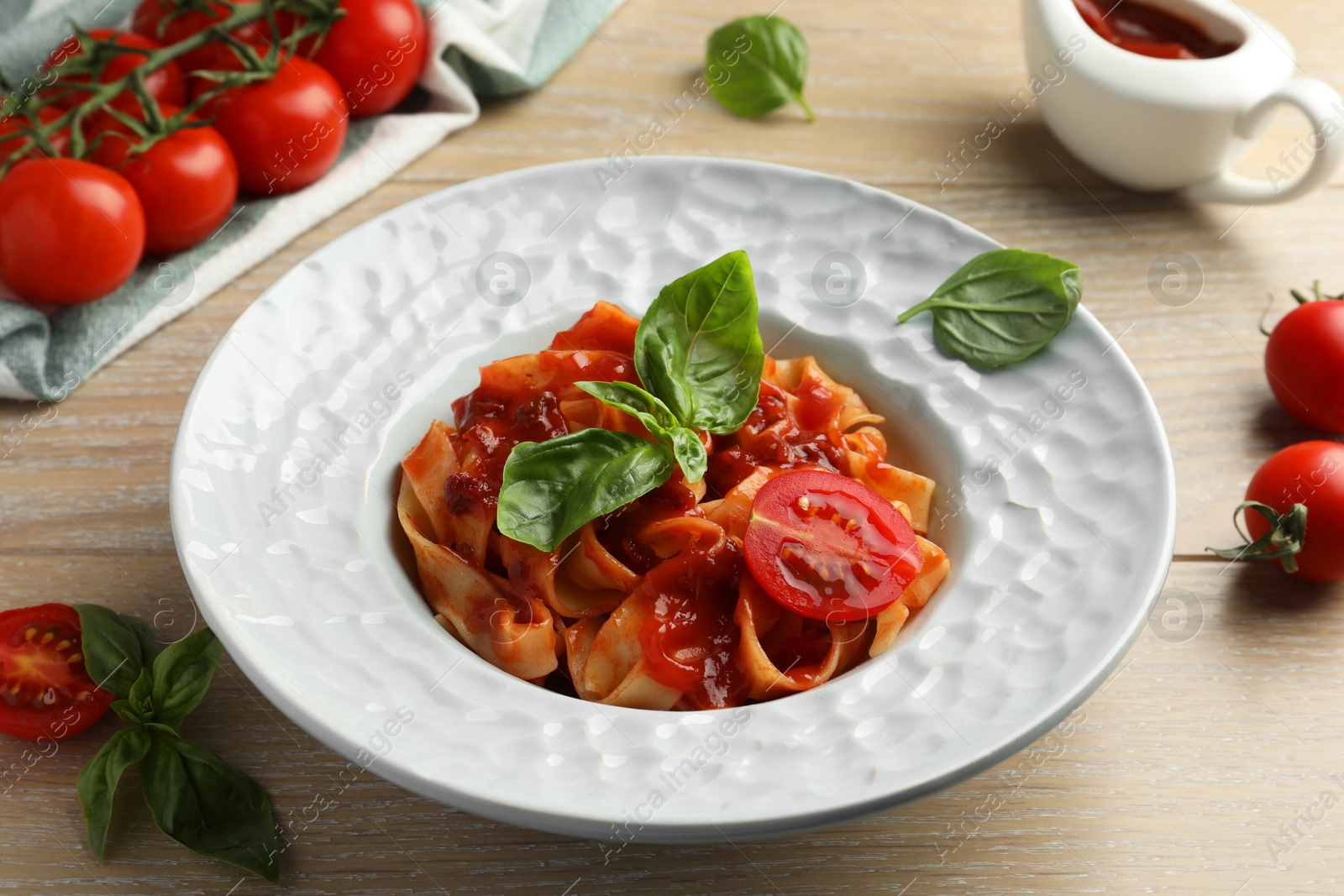 Photo of Delicious pasta with sauce, tomato and basil on wooden table, closeup