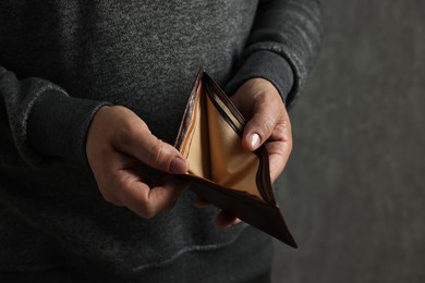 Photo of Man with empty wallet on dark background, closeup