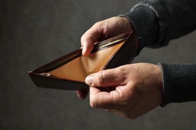 Photo of Man with empty wallet on dark background, closeup