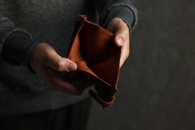 Photo of Man with empty wallet on dark background, closeup