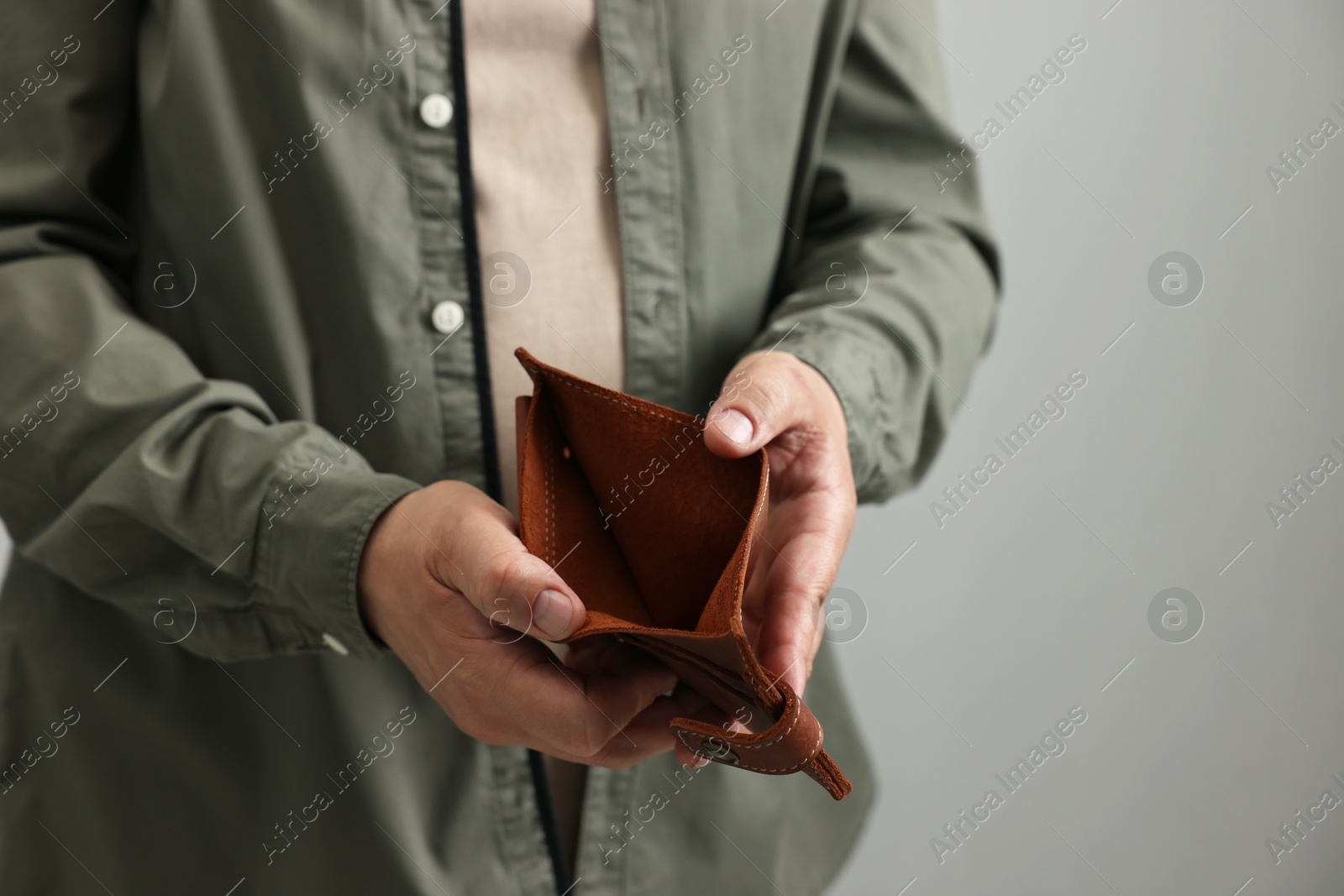 Photo of Man with empty wallet on grey background, closeup