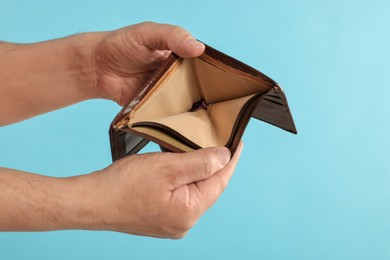 Photo of Man with empty wallet on light blue background, closeup. Space for text