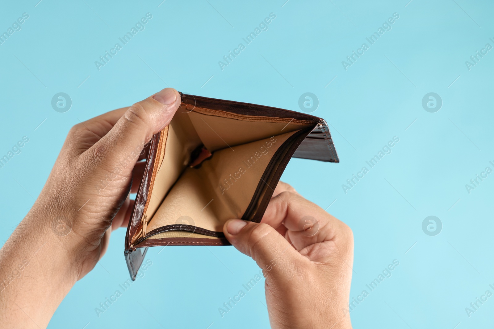 Photo of Man with empty wallet on light blue background, closeup. Space for text