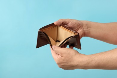 Photo of Man with empty wallet on light blue background, closeup. Space for text