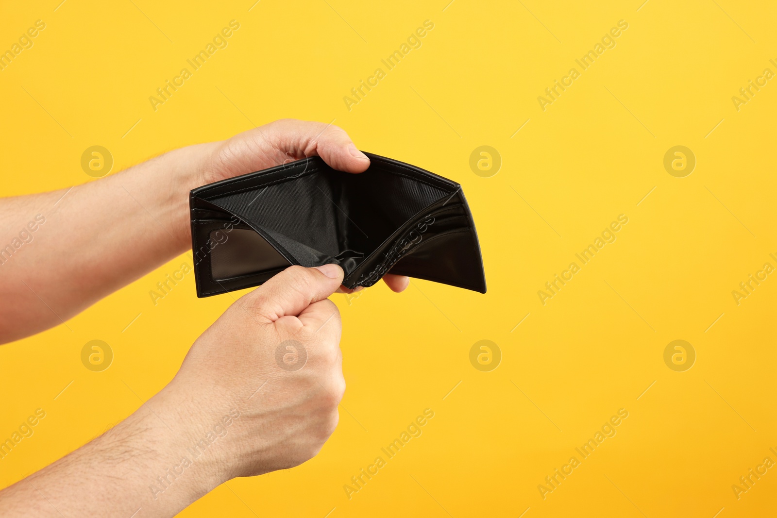 Photo of Man with empty wallet on yellow background, closeup. Space for text