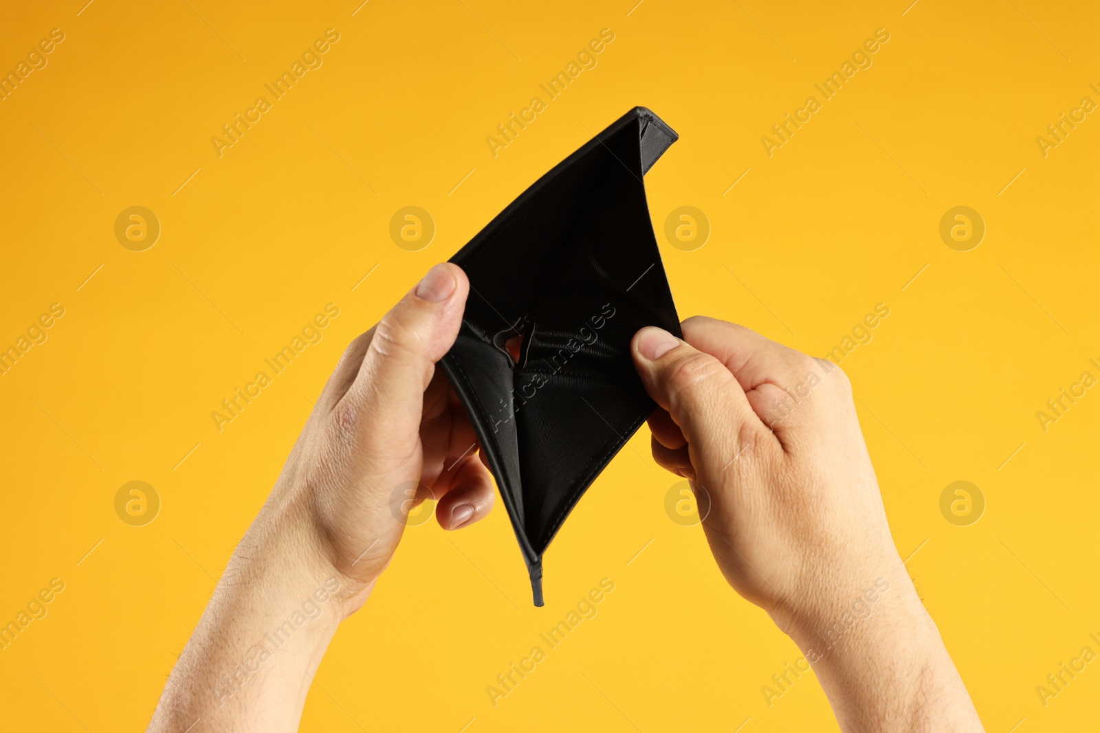 Photo of Man with empty wallet on yellow background, closeup