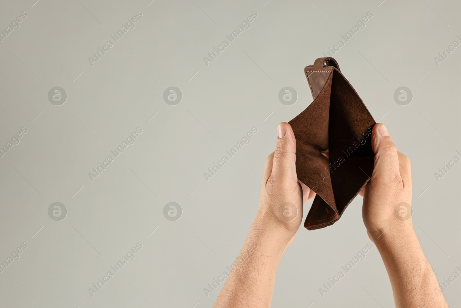 Photo of Man with empty wallet on grey background, closeup. Space for text