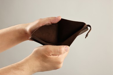 Photo of Man with empty wallet on grey background, closeup