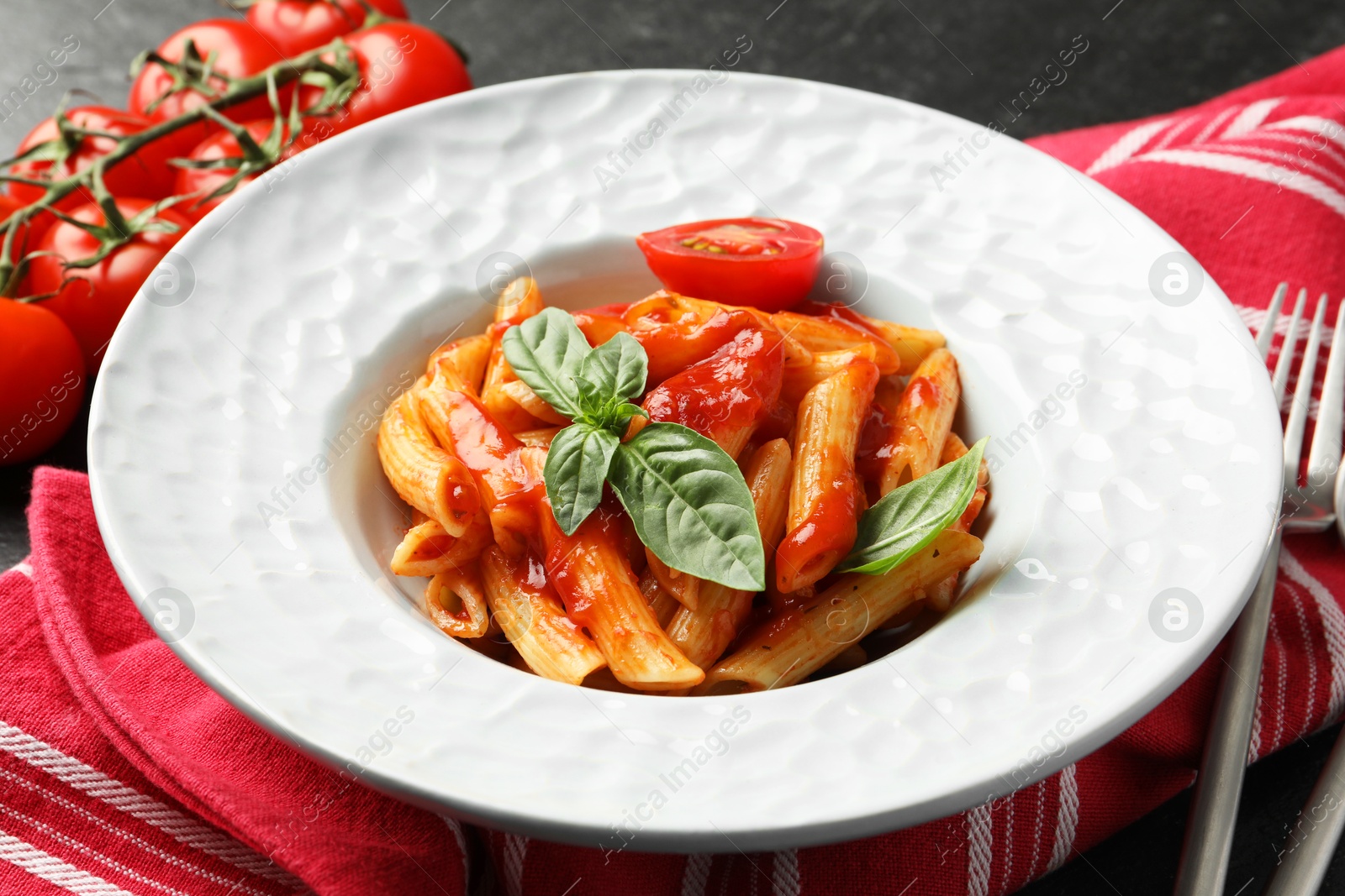 Photo of Delicious pasta with tomato sauce and basil served on black table, closeup