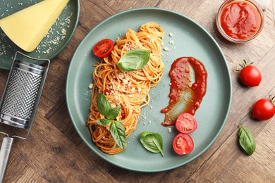 Photo of Delicious pasta with tomato sauce, basil and cheese on wooden table, flat lay