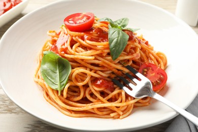 Taking delicious pasta with tomato sauce and basil at table, closeup