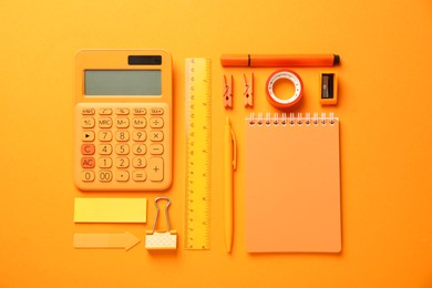 Different stationery on orange background, flat lay