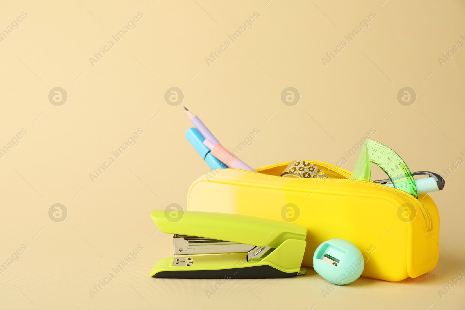 Photo of Green stapler and other stationery on beige background, space for text