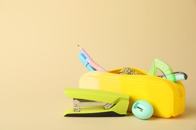 Photo of Green stapler and other stationery on beige background, space for text