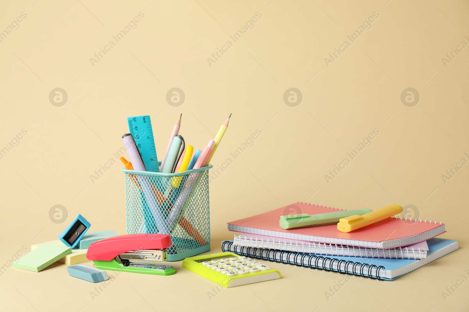 Photo of Bright stapler and other stationery on beige background, space for text