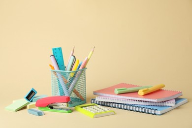 Bright stapler and other stationery on beige background, space for text