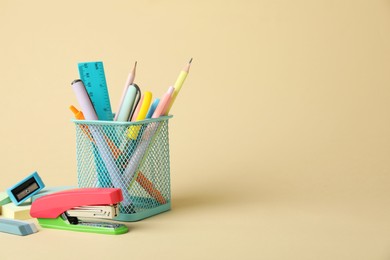 Bright stapler and other stationery on beige background, space for text