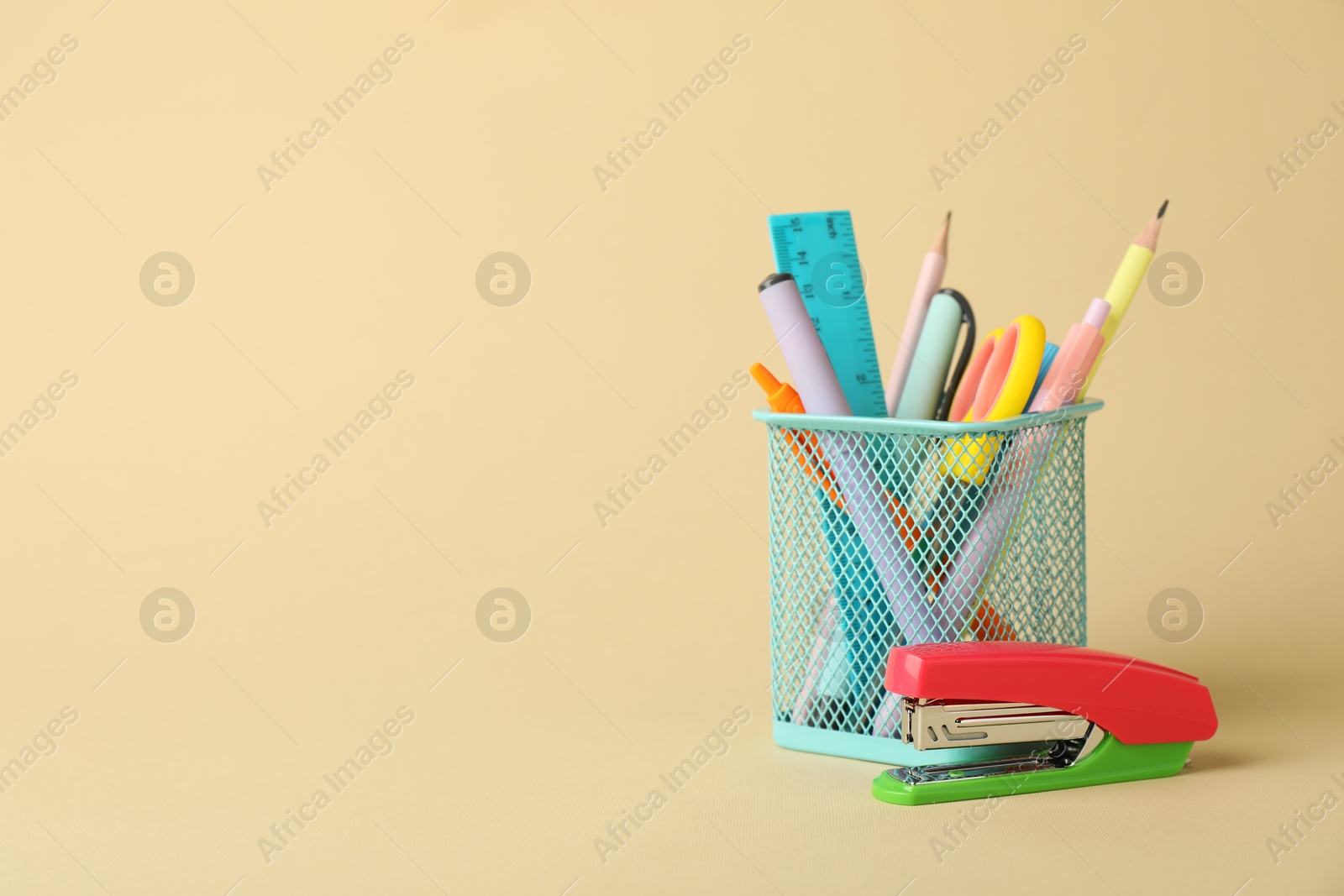 Photo of Bright stapler and other stationery on beige background, space for text