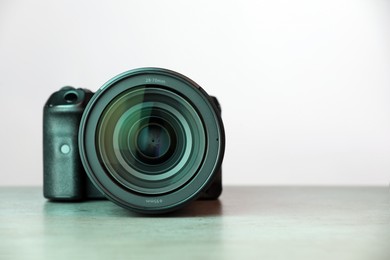 Photo of Modern photo camera on grey table, space for text. Photographer's equipment