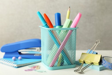 Stapler, holder and other different stationery on white table