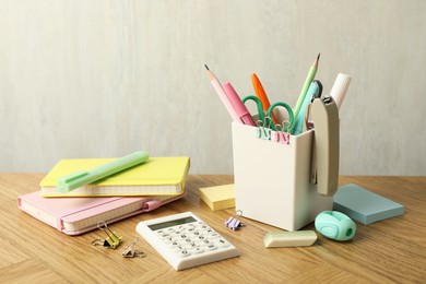 Photo of Stapler, holder and other different stationery on wooden table