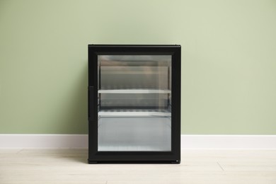 Photo of Empty modern mini refrigerator near olive wall