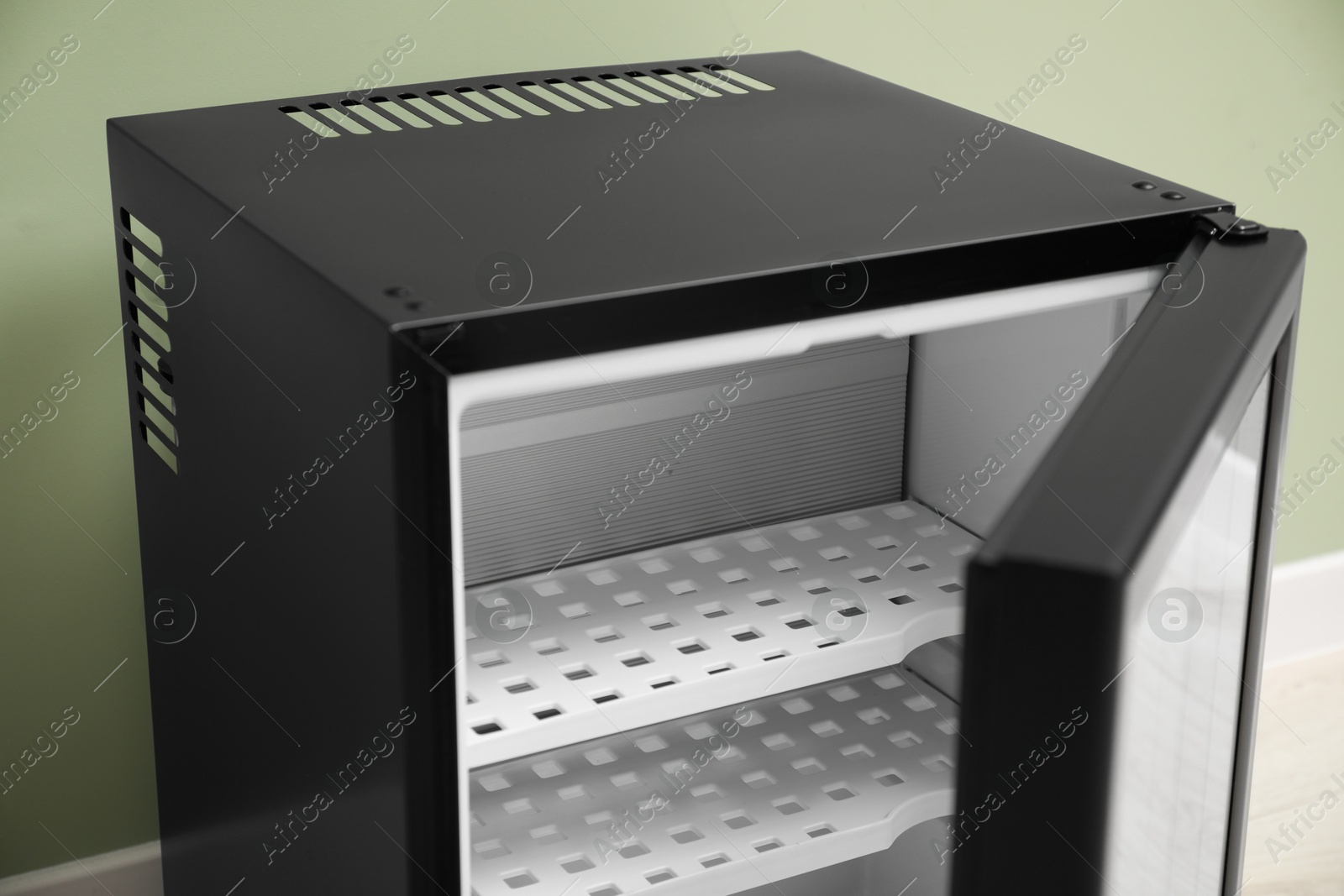 Photo of Empty modern mini refrigerator near olive wall