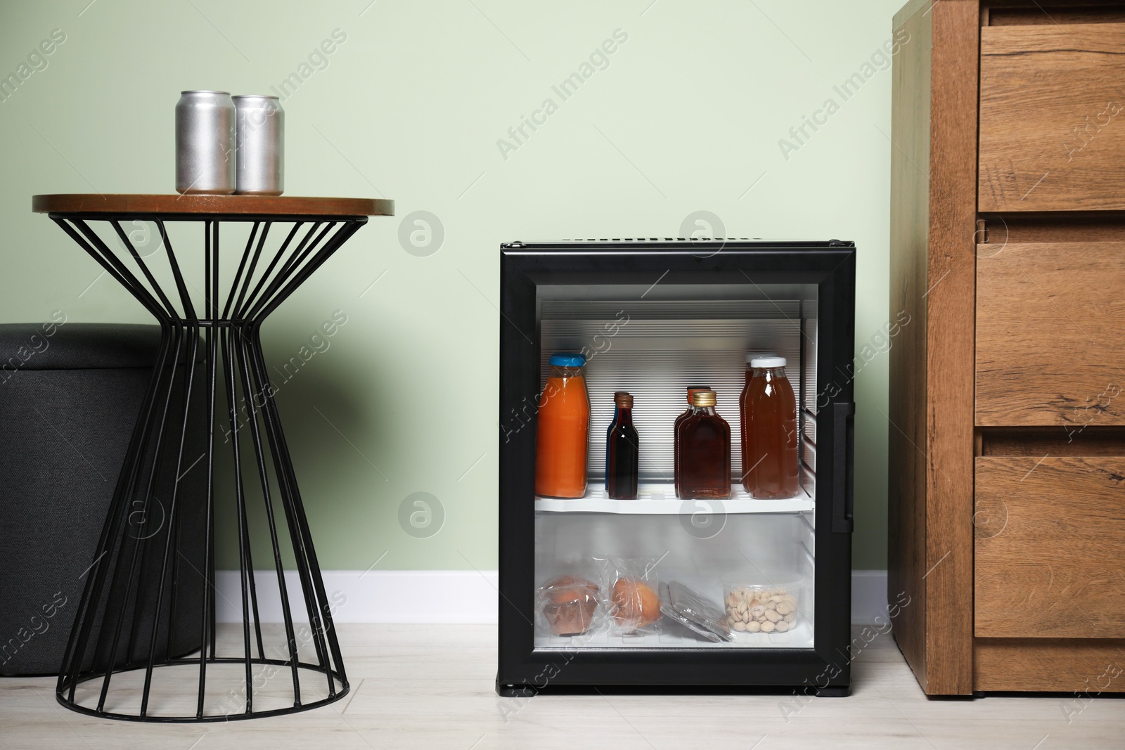 Photo of Mini refrigerator with different drinks and snacks indoors