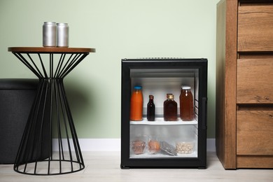 Mini refrigerator with different drinks and snacks indoors