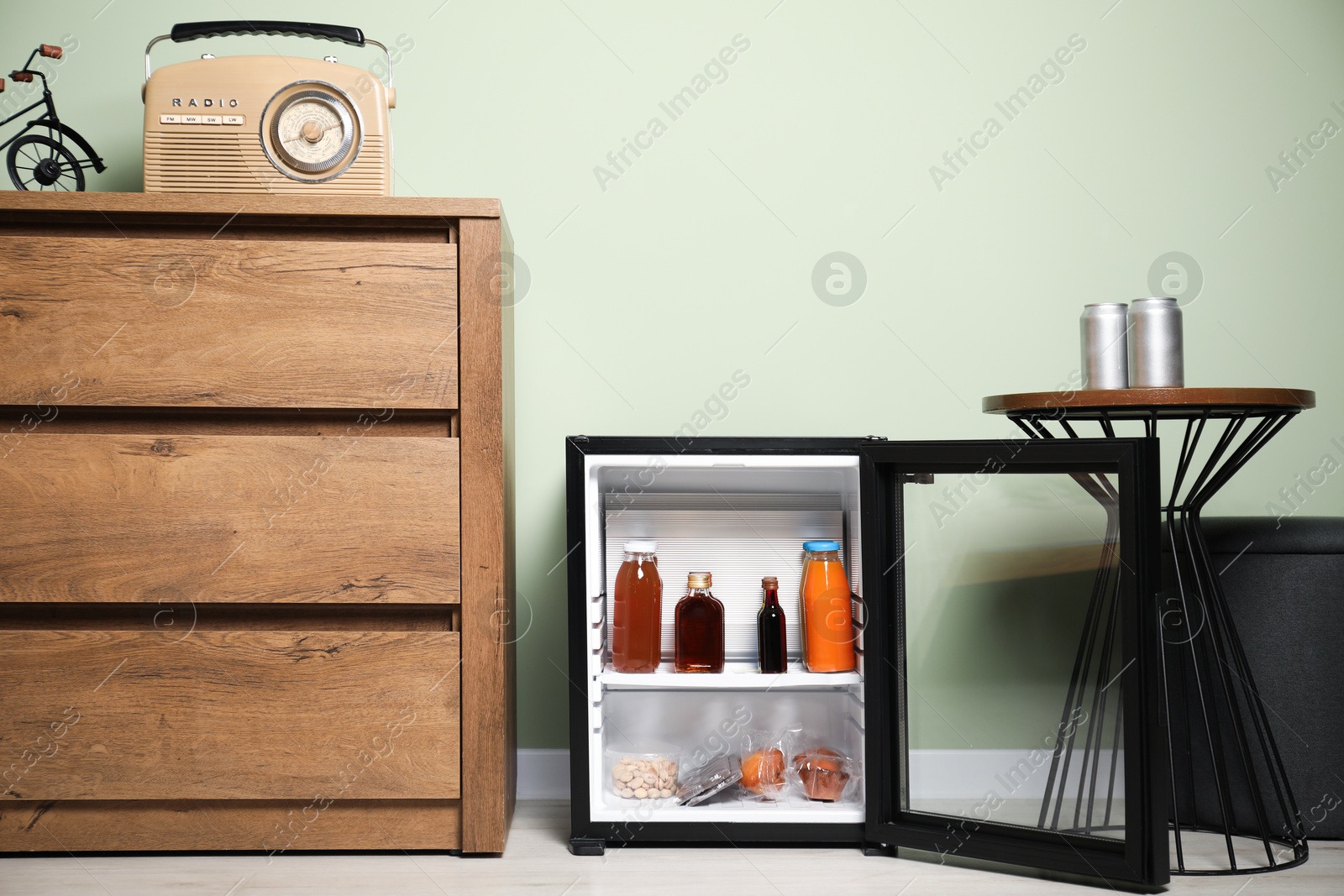 Photo of Mini refrigerator with different drinks and snacks indoors