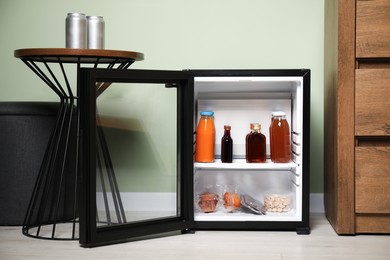 Mini refrigerator with different drinks and snacks indoors