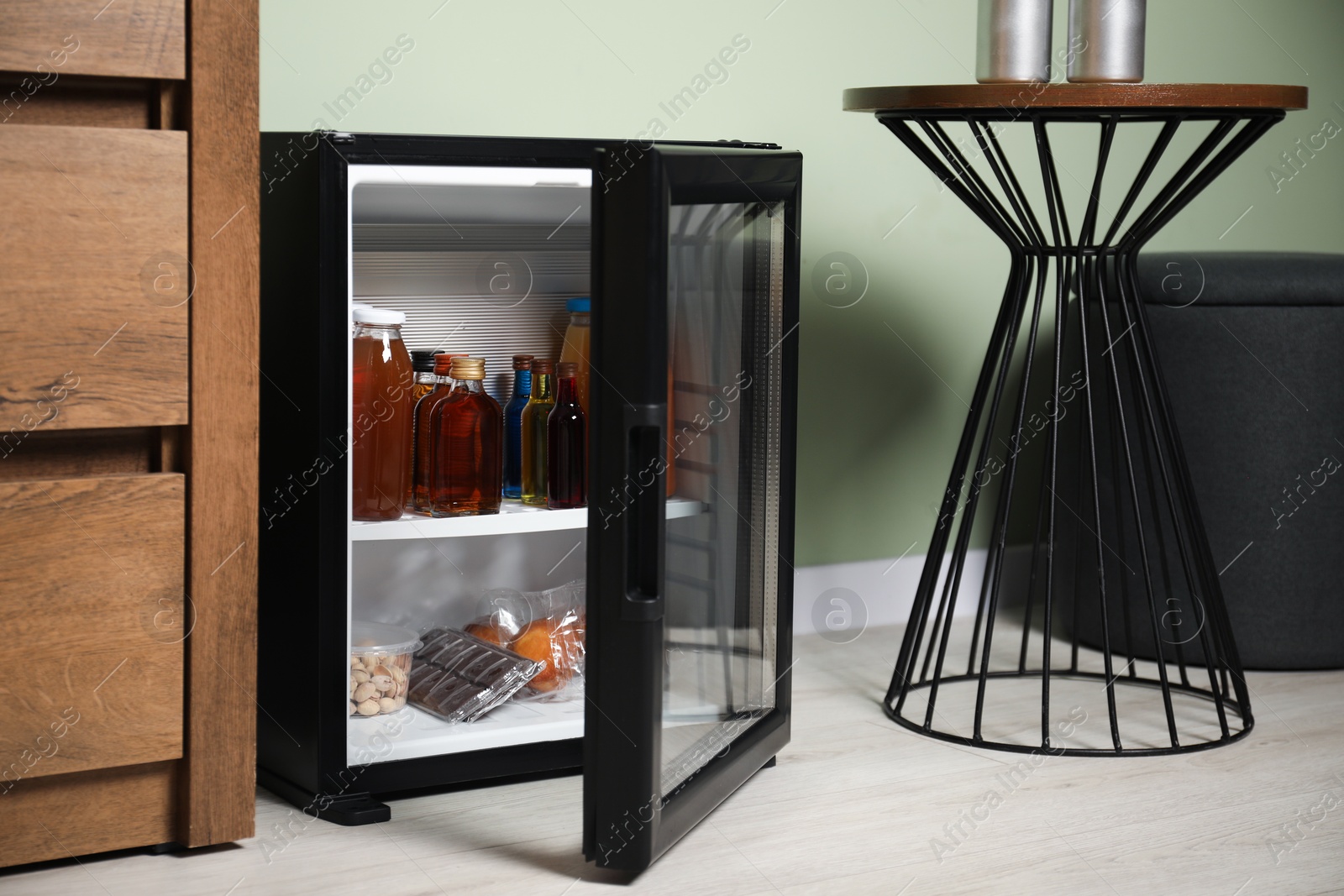 Photo of Mini refrigerator with different drinks and snacks indoors